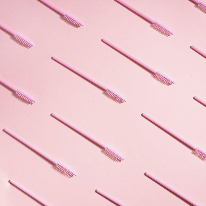 Multiple pink brushes pointed diagonally to the bottom right on a pink background